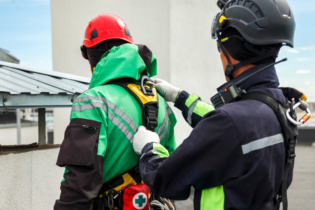 A safety instructor checking a worker's fall protection harness